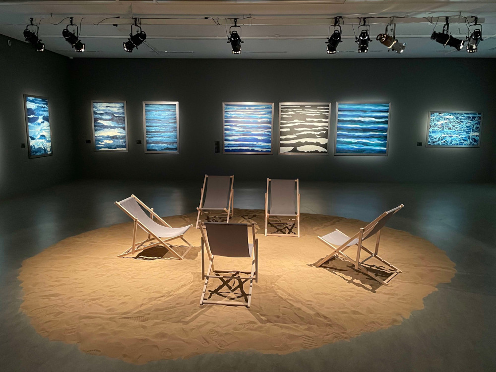 Obrazy z serii Błękitny wyeksponowano w sali z morskim piaskiem i leżakami plażowymi.